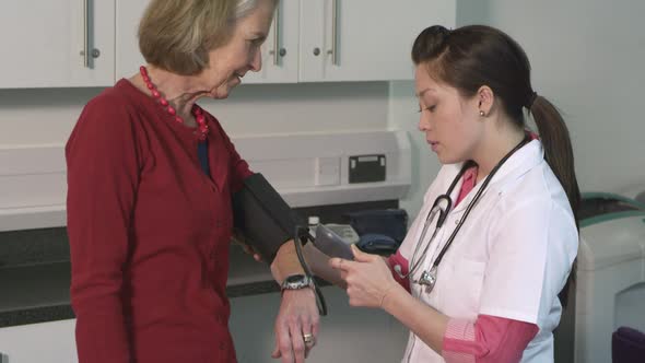 CU TU Female doctor checking pulse trace to senior patient in hospital / London, United Kingdom