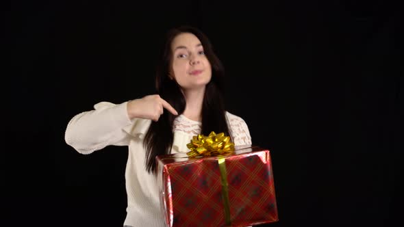 Young Woman with a Gift Box on Black Background. Gift Box with White Ribbon for Happy New Year