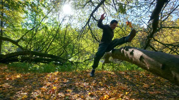 An Man Doing A Jump Exhibition Over A Tree Trunk During Autumn Season In Lithuania- Tracking Shot