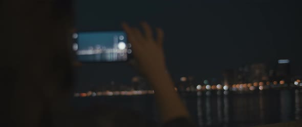 Woman taking photos of a city at night