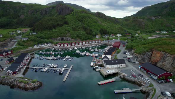 Aerial backwards shot of a Norwegian marina harbor in Helgeland, Tonnes, clouds reflecting on the su