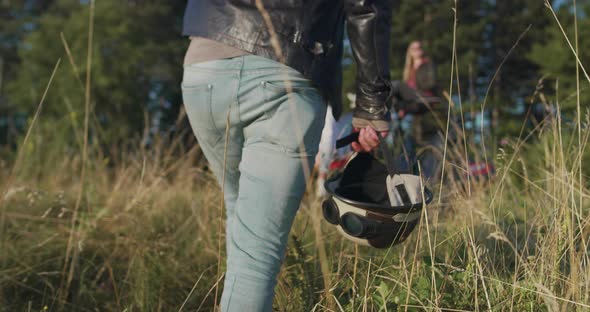 Close Up of Hipster Man Holding Hemlet and Going Towards Group of Friend That are Having Fun in