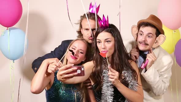 Group of happy friends taking selfie in photo booth