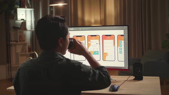 Male Mobile Application Developer Works And Drinking Coffee With Graphics On His Personal Computer