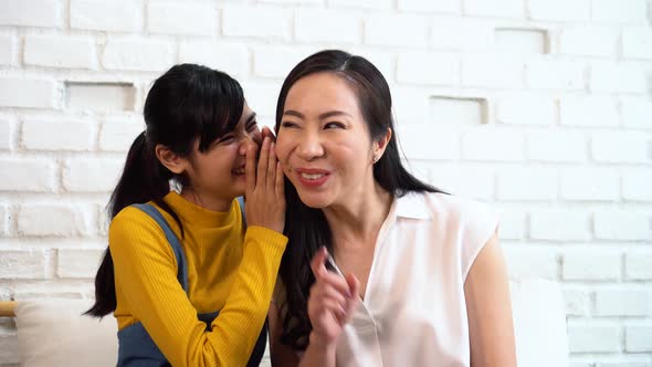 Asian Family of Teenage Girl Gossiping at Mature Woman's Ears at Home
