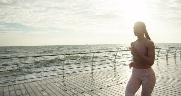 Woman in Sportswear Goes Jogging Along Embankment By Sea