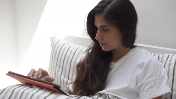 Young Woman Reading a Book on a Modern Portable Tablet and Smiling