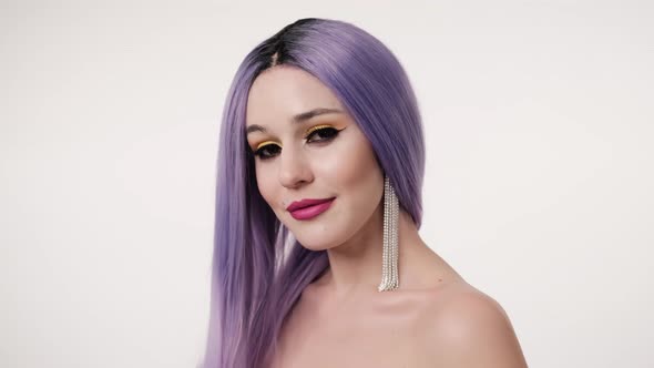 Portrait of beautiful happy woman in lilac wig and posing over light background