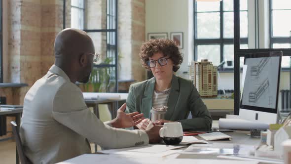 Multiethnic Architects Chatting over Coffee in Office