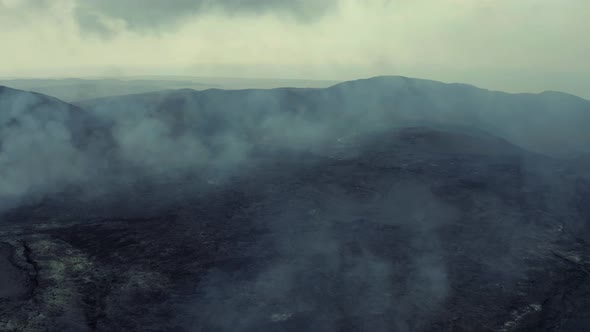 Drone Flies Over Hot Lava Field With Smoke After Volcano Eruption. low aerial