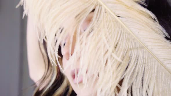 Young Brunette Woman Looks Through Feather at Costume Party