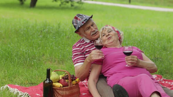 Family Weekend Picnic in Park. Active Senior Old Caucasian Couple Sit on Blanket and Drink Wine