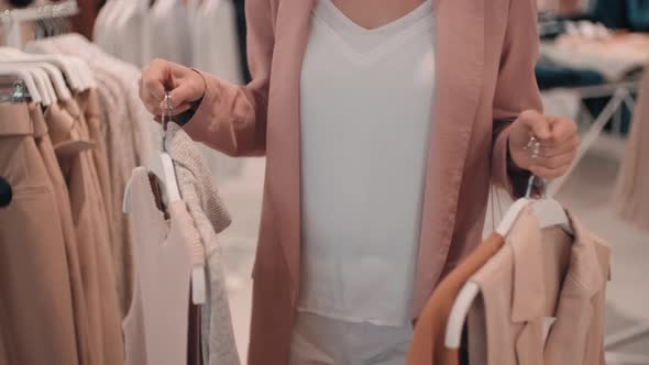 Unrecognizable Woman Carrying Clothes on Hangers