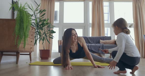 Mom is Doing Stretching Yoga Online at Home Laptop on the Floor While Active Energetic Child