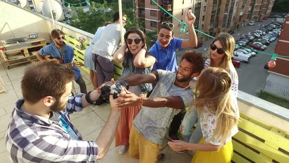 Happy people taking photos and laughing at the rooftop, musician playing guitar