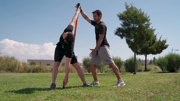 Fitness Trainer in Functional Training Accompanies a Man in Exercises and Rehabilitation on His Back