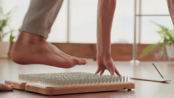 Unrecognizable Feet Standing On Nail Board