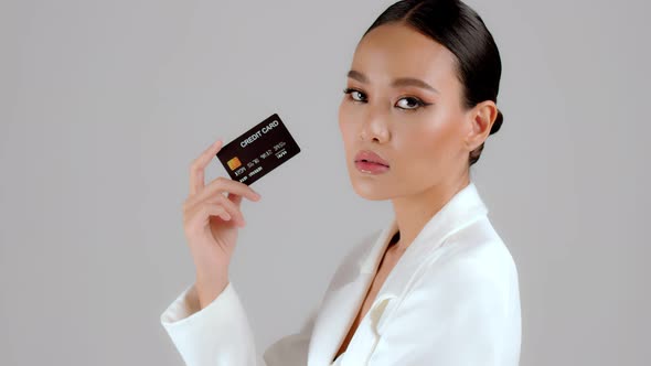 Beautiful Asian businesswoman showing credit card and looking at camera