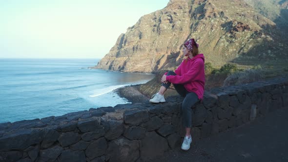 A Woman Walks Next to the Ocean Enjoying the Calm Scenery Against the Background of the Volcanic