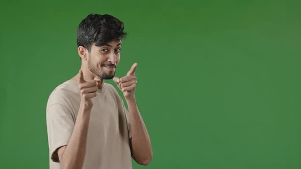 Positive Smiling Arab Young Man Guy Stand in Green Studio Showing Hey you Gesture Pretending