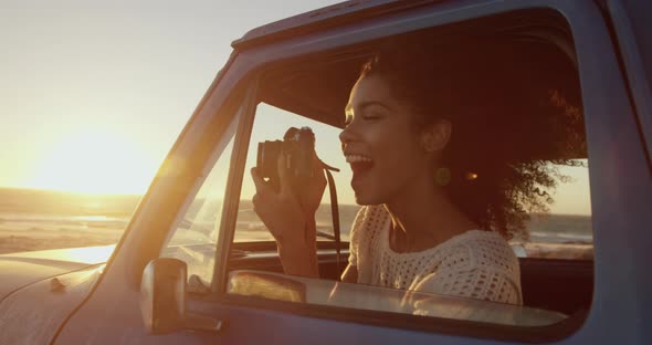 Woman taking photo with digital camera in pickup truck at beach 4k