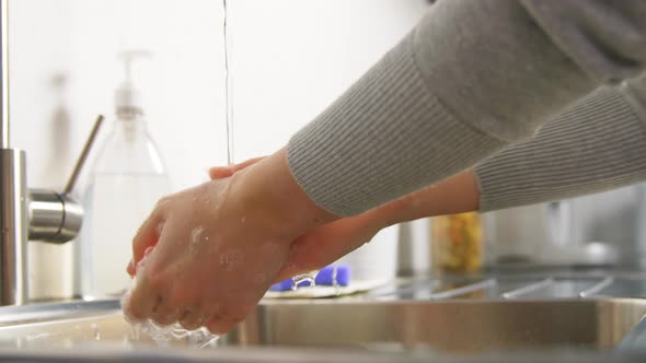 Woman Washing Hands with Liquid Soap in Kitchen