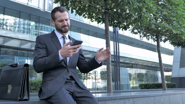 Beard Businessman Upset for Loss while Using Smartphone