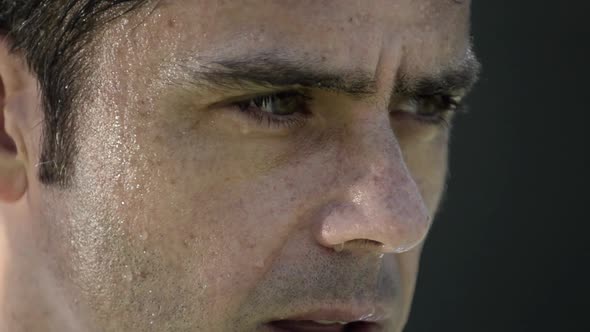 Extreme close-up portrait of a man serving a tennis ball.