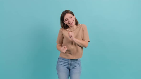 Young Beautiful Woman Dancing and Posing Over Turquoise Background.