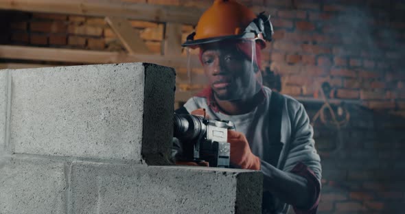 Serious Black Man Drilling Concrete Block