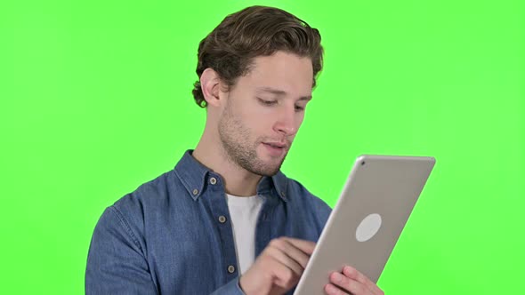 Focused Young Man Using Digital Tablet on Green Chroma Key