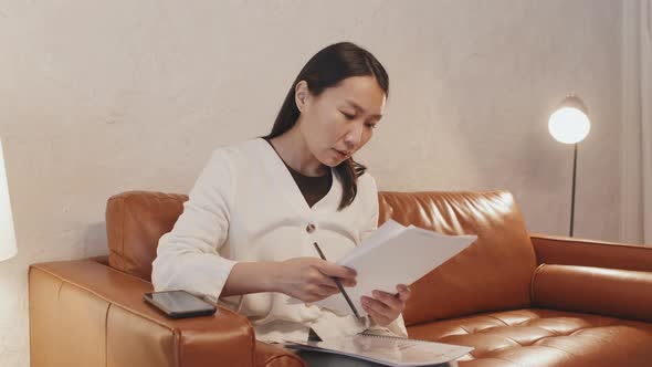 Asian Woman Doing Paperwork on Couch