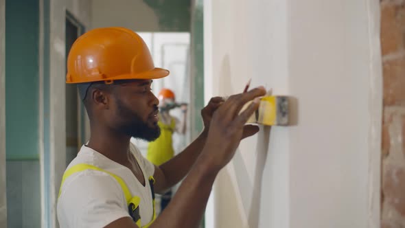 African Male Worker Checking Level of the Wall with the Bubble Level Tool