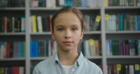 Adorable Blonde Girl Looks in Camera Smiling in Library