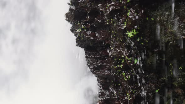 A Closeup of Rocky Stone From Which Streams of Water Flow Agains Power Waterfall