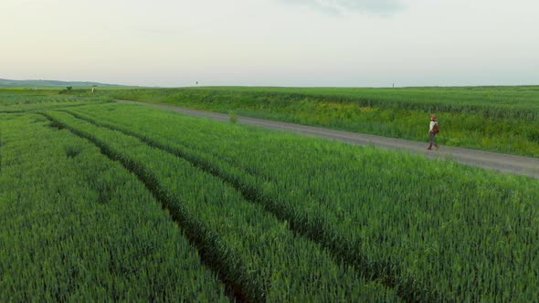 Young girl with a backpack near a farm with green energy windmills, aerial view