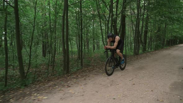Man Triathlete Rides a Bike Pro Cyclist Rides on a Forest Road Preparation for Competitions and