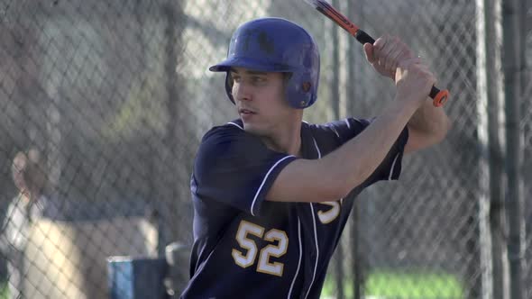 A young man practices baseball at the batting cages.