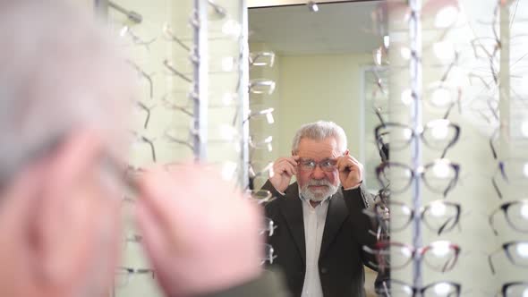 an Elderly Man Tries on and Chooses Glasses in the Optics Salon