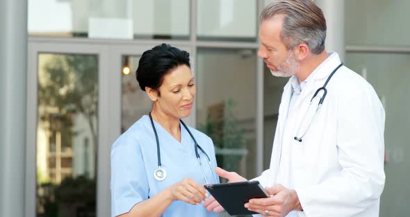 Two doctors discussing over digital tablet