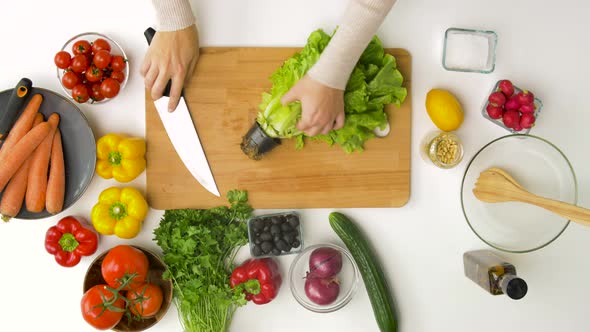 Woman Adding Lettuce To Salad Bowl at Home Kitchen