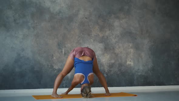 Flexible Professional Gymnast Bends To the Floor with Arching in the Back in a Loft Studio