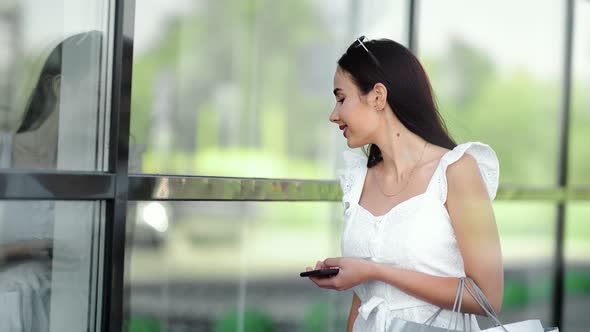 Smiling Fashion Young Woman Looking at Glass Window Showcase of Trendy Clothing Shop