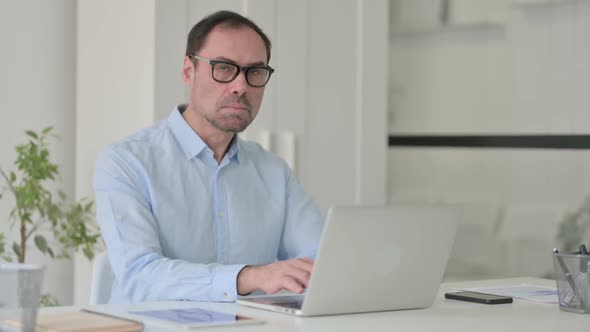 Middle Aged Man with Laptop Showing Thumbs Up