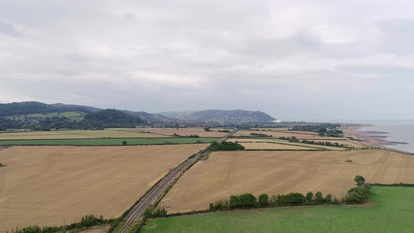 Wide aerial shot tracking forward between Blue Anchor and Minehead in Somerset. A steam engine  driv