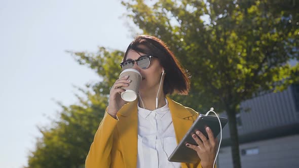 caucasian young business woman using tablet computer while stands near office centre