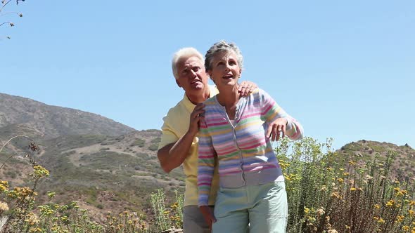 Mature couple in rural setting, looking up and pointing