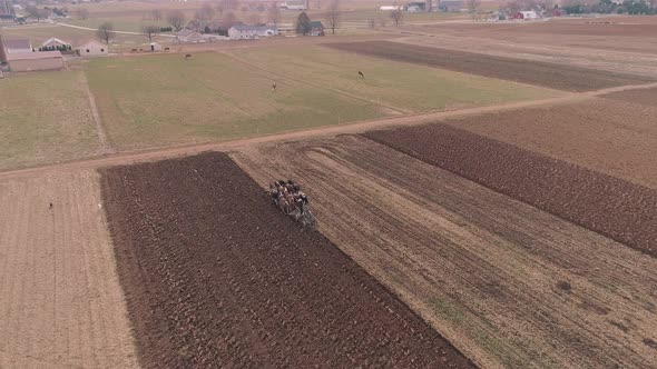 Aerial View of Amish Farm Worker Turning the Field in Early Spring as Seen by a Drone