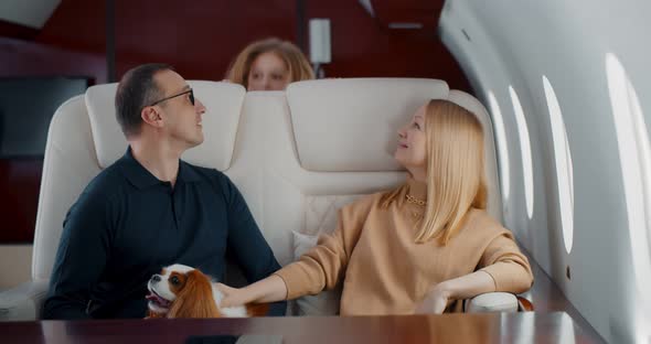 Happy Wealthy Family with Preteen Daughter and Cocker Spaniel Dog Flying Together on Private Jet