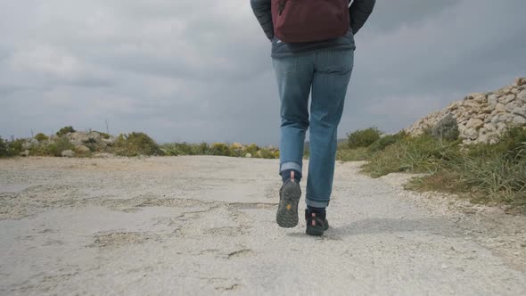 Close-up of  the legs of a hiker walking on a rural road in the mediterranean nature on a cloudy win